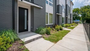 A modern apartment building with a grey facade, numbered 808, featuring a clean, straight pathway leading to the entrance. - Modern 3 3 in East Nash 10min to Broadway (Nashville)