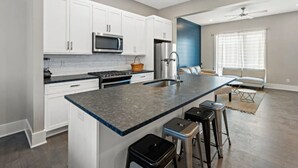 A modern kitchen with white cabinets, a granite countertop, stainless steel appliances, and a bar stool area. - Modern 3 3 in East Nash 10min to Broadway (Nashville)