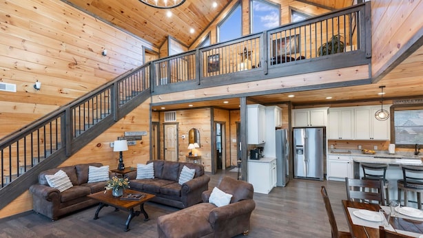 A spacious living area with a wooden interior, a staircase, a kitchen, and a dining area. - Luxury Brand New Cabin 5b 5 5ba w Arcade Theater (Sevierville)