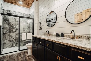 A bathroom with a shower, toilet, and vanity with a marble countertop and black cabinets. - Brand New 4 4 Minutes to Dollywood Hot Tub (Pigeon Forge)