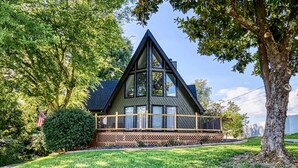 A triangular-shaped house with a wooden deck and a large window. - Unique 4bed 3bath A-frame (Kodak)