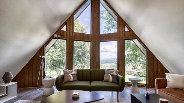 A modern loft bedroom with a large skylight, a green sofa, and a wooden floor. - Unique 4bed 3bath A-frame (Kodak)