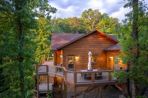 A wooden cabin with a deck and outdoor seating area surrounded by trees. - Luxury 3 2 5 Cabin Lake Views Theatre Gameroom (Bryson City)