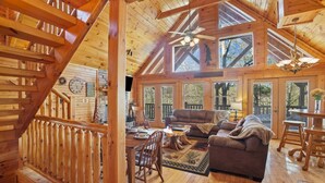 Ein Holzblockhaus-Interieur mit Essbereich, einer Couch und einer Treppe.