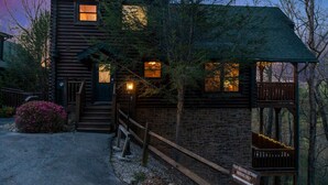 Ein rustikales Blockhaus mit Veranda, Treppe und einem Schild, das einen ganzjährigen Parkplatz kennzeichnet.