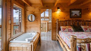 A wooden cabin interior with a wooden bed, a wooden bathtub, and a large window. - 47majestic Luxe 3bd 3 5ba w Spectacular Views (Sevierville)