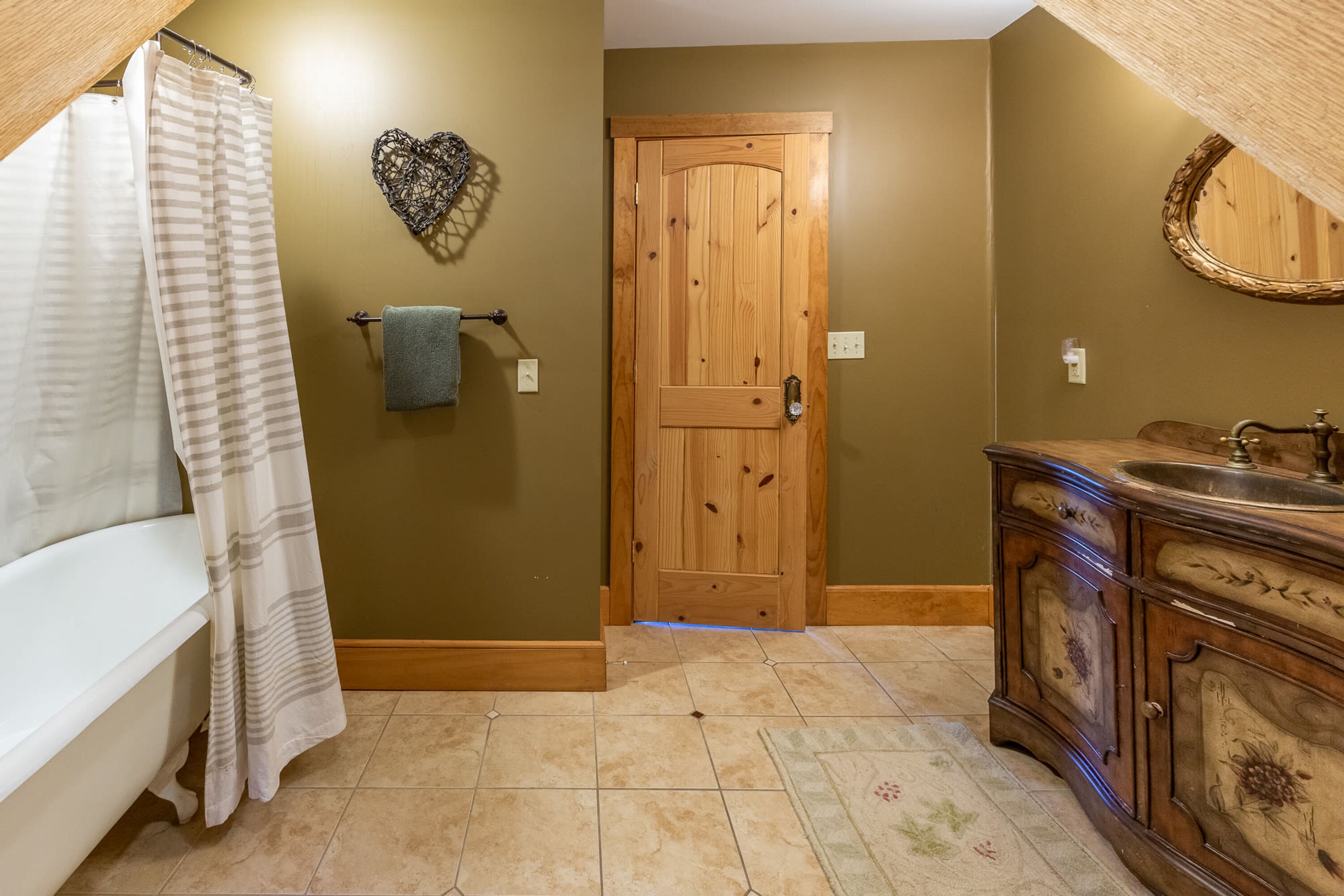A bathroom with a bathtub, wooden door, and a vanity with a sink.