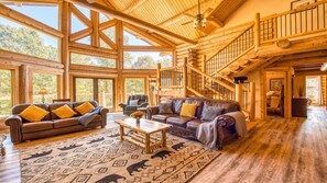A spacious log cabin interior with a large living area, a wooden staircase, and large windows. - Slps 24 12m Town 7acre Huge Yard Theatre Gmroom (Sylva)