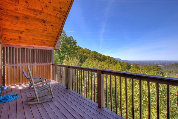 A wooden deck with a view of a forested landscape.