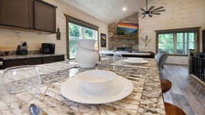 A kitchen with a marble countertop, a white vase, and a dining area with a table set for two.