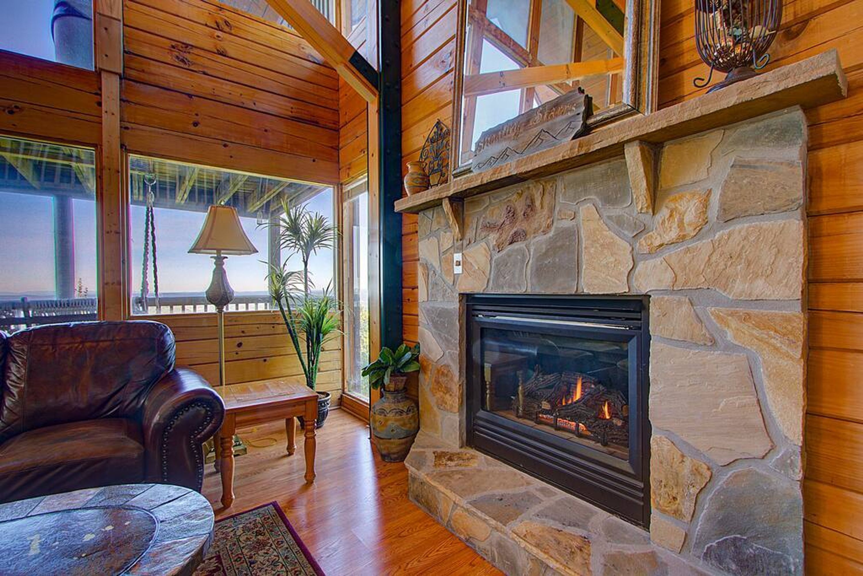 Ein gemütliches Wohnzimmer mit Kamin aus Stein, Ledersofa und Holzbalken.