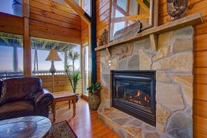 Ein gemütliches Wohnzimmer mit Kamin aus Stein, Ledersofa und Holzbalken.