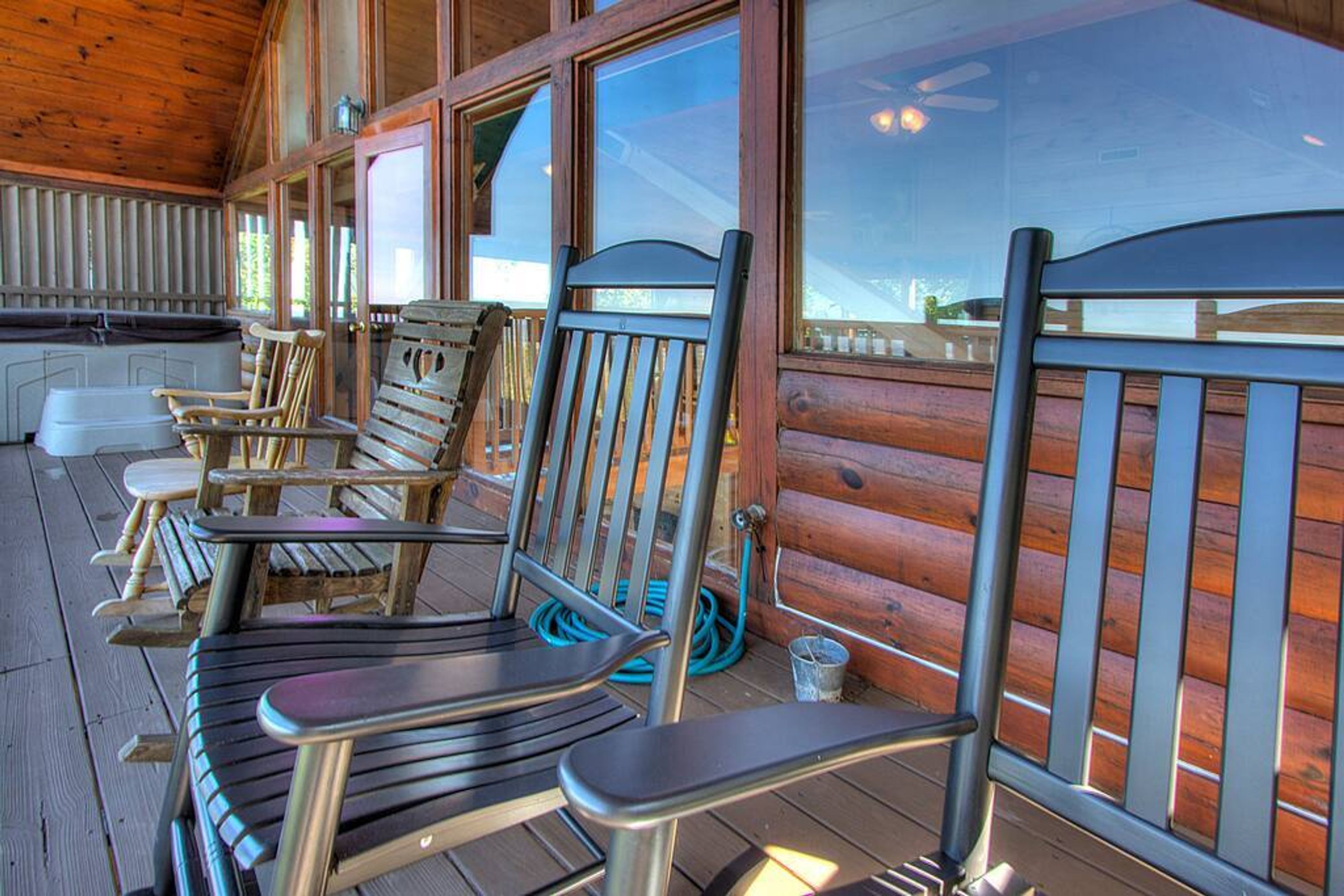 A wooden deck with outdoor seating, including chairs and a bench, and a view of the surrounding landscape.