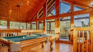 A wooden pool table in a room with large windows and a wooden deck. - Mountain Majesty With Spectacular Views (Sevierville)