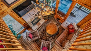A cozy wooden cabin interior with a fireplace, a round coffee table, and comfortable seating. - Mountain Majesty With Spectacular Views (Sevierville)