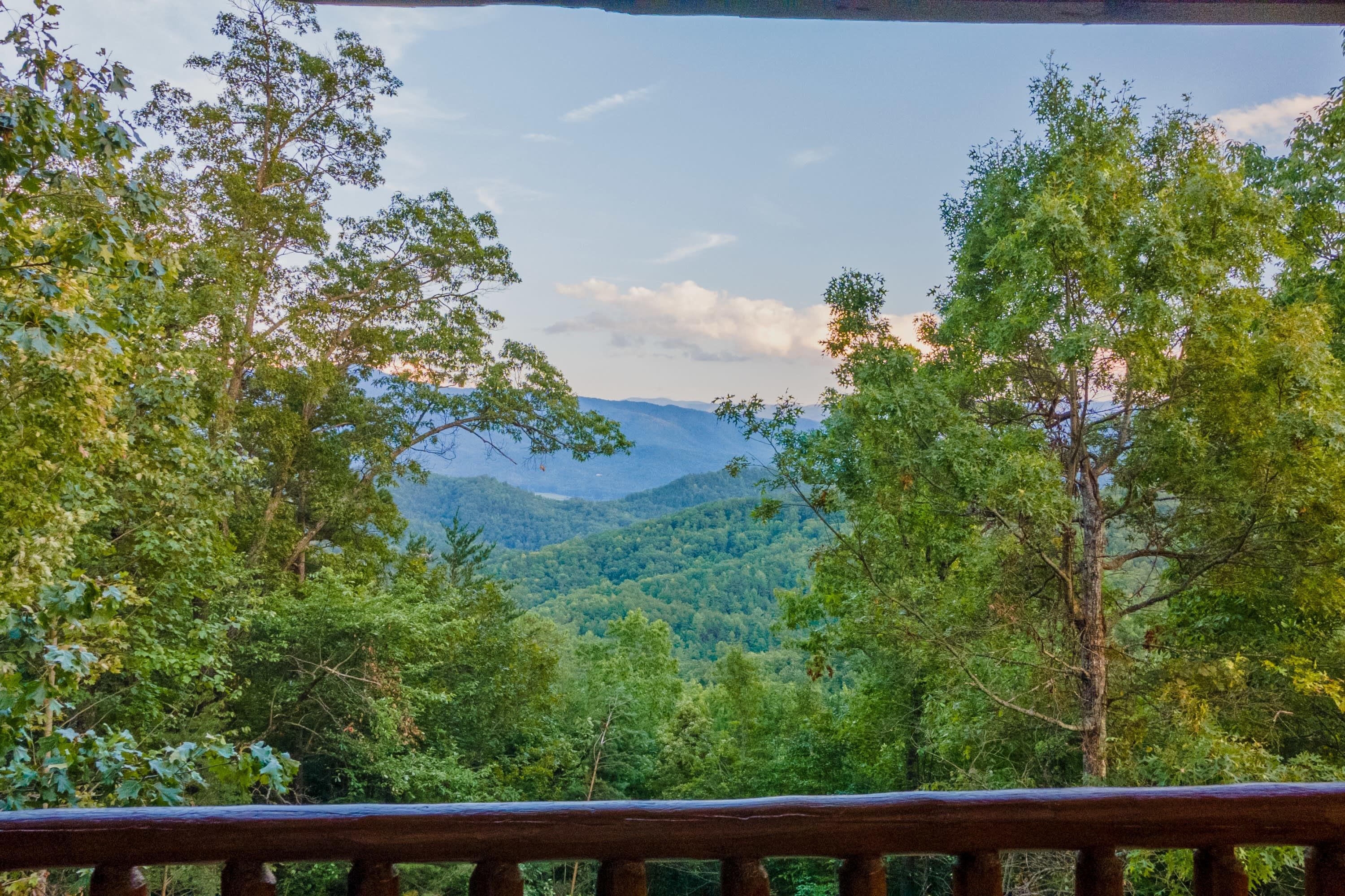A view from a wooden deck overlooking a forested mountain range.