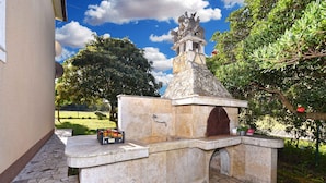 An outdoor stone structure with a fountain, a bench, and a small table with books and a bottle. - Holiday apartment with air conditioning (Rovinj)