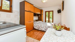 A compact kitchen with a built-in stove, wooden cabinets, and a window. - Holiday apartment with air conditioning (Rovinj)