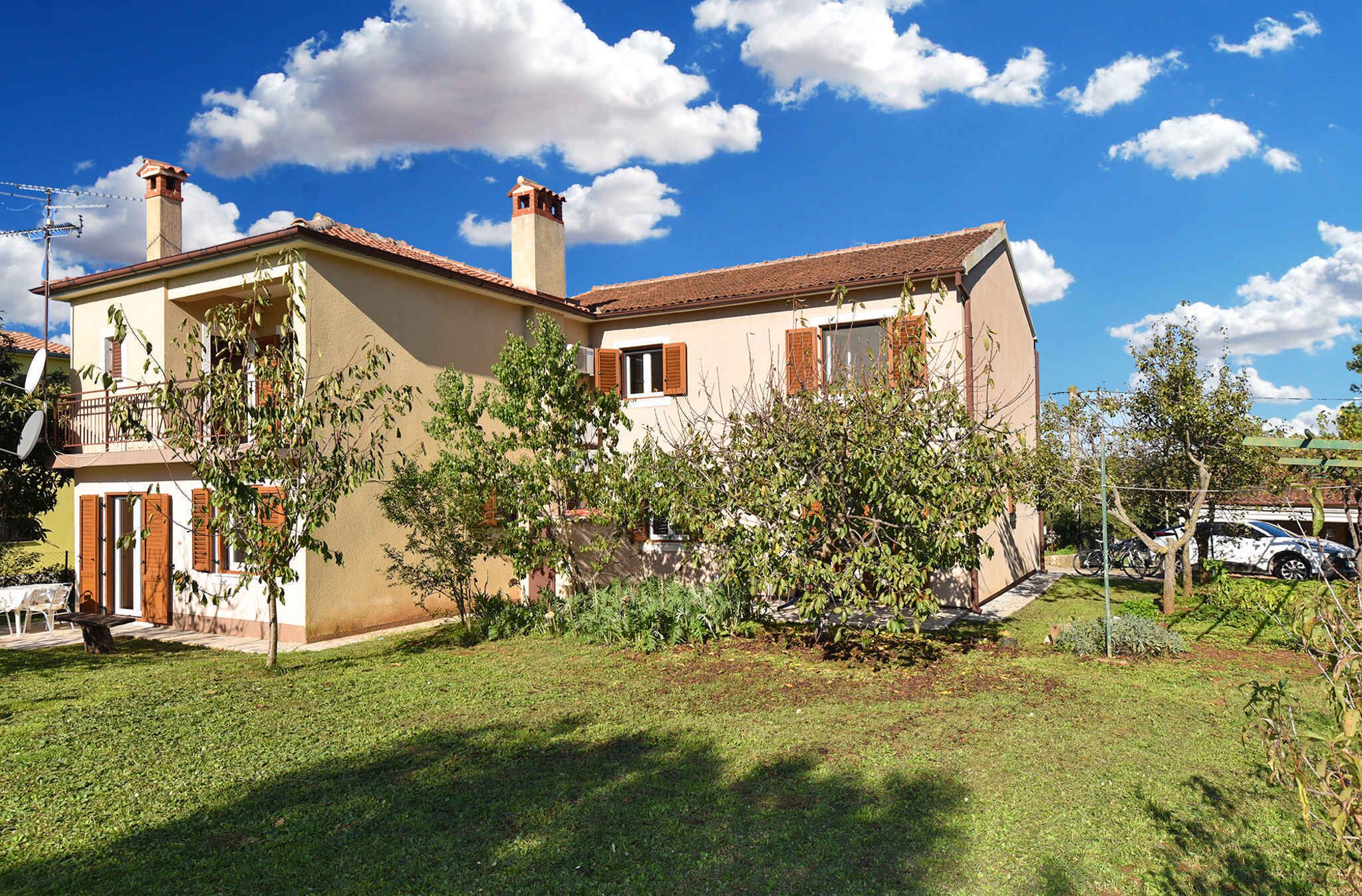 Une maison à deux étages, avec un toit en tuiles, une cheminée et un petit balcon.