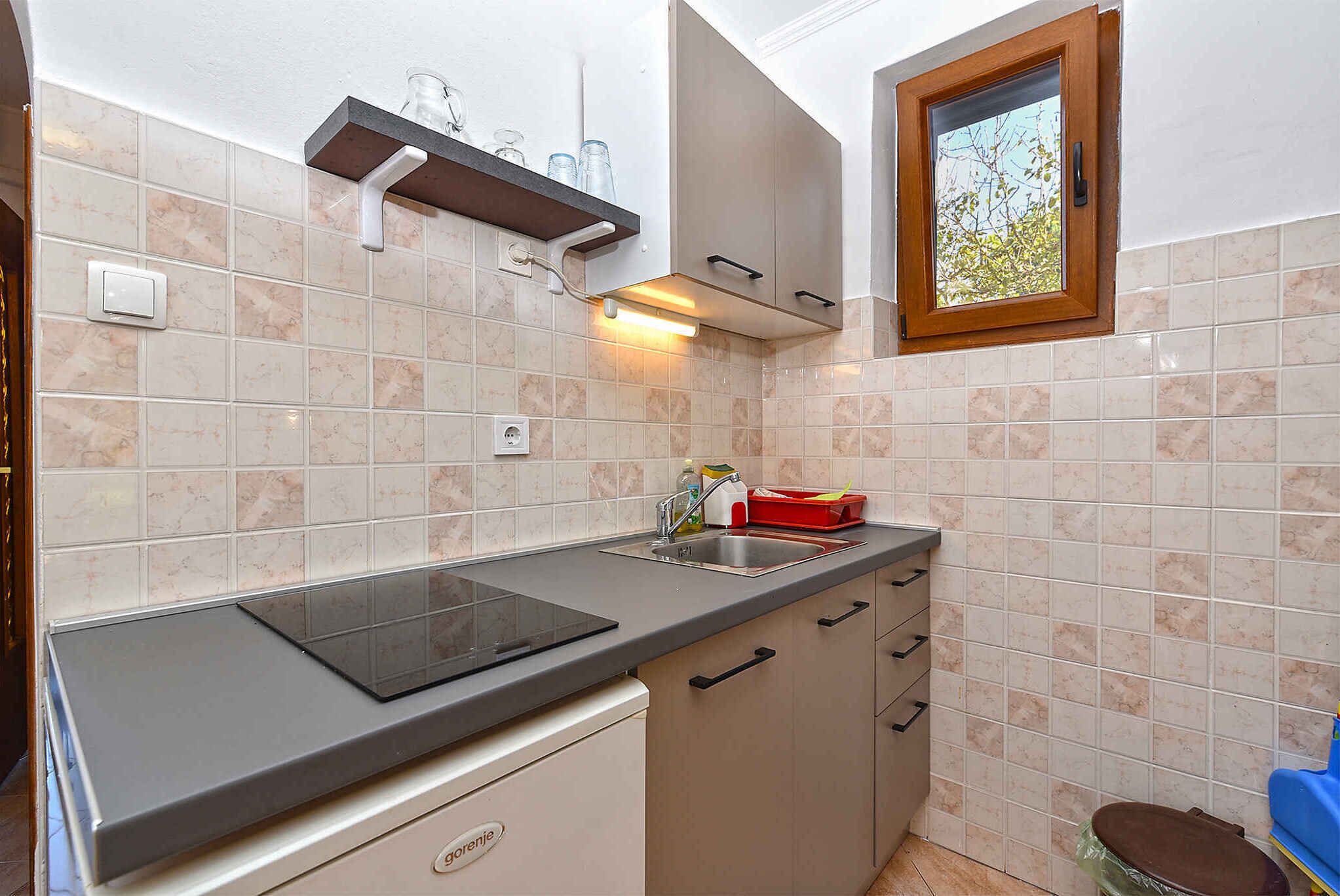 A compact kitchen with a built-in stove, a sink, and a window.