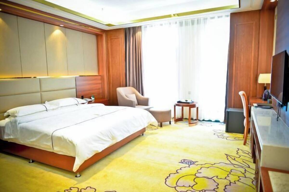Una habitación de hotel con una cama grande, una silla, una mesita y un televisor.