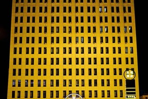 Un grand immeuble avec une façade constituée d’une grille de fenêtres et une horloge sur le côté droit.