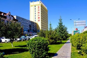 Un hotel con un patio central, rodeado de vegetación y coches aparcados.