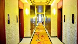 A hotel hallway with a floral carpet, doors on both sides, and a bright ceiling. - Tianyue Hotel (Fuyun)