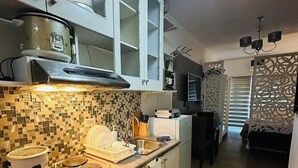 A modern kitchen with white cabinets, a tiled backsplash, and a black countertop. - Taguig 1 Bedroom with Balcony Near Bgc (Taguig)