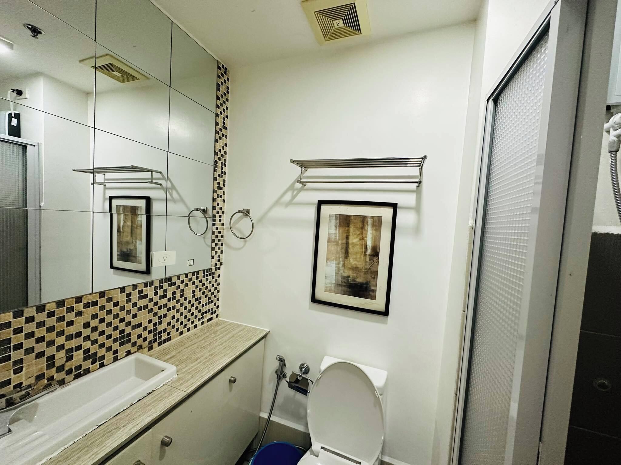 A bathroom with a tiled backsplash, a sink, a toilet, and a shower area.