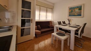 A compact living space with a kitchenette, a dining area with a table and chairs, and a sofa.