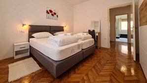 A bedroom with a large bed, bedside tables, a mirror, and a wooden floor.
