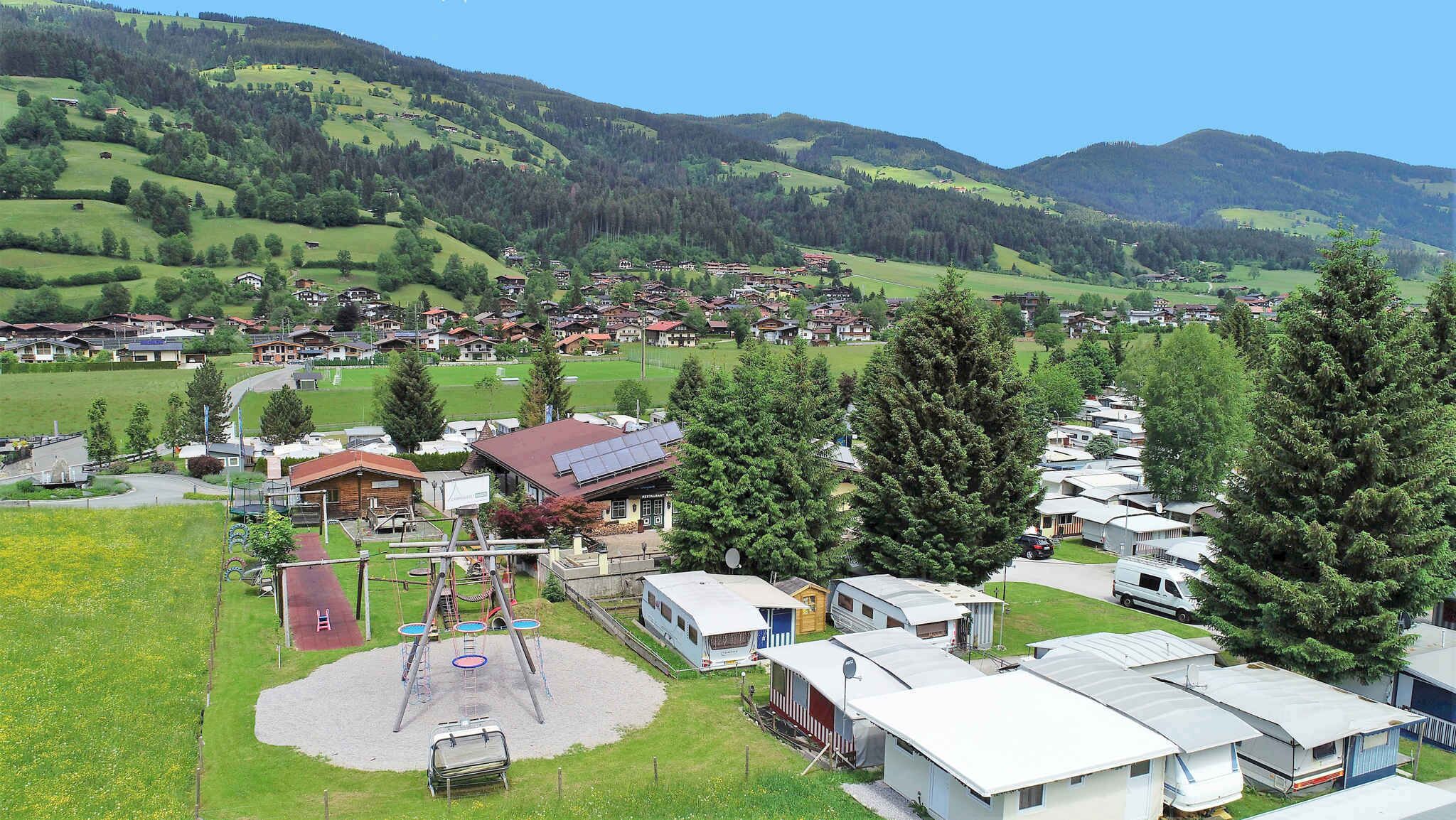 A campground with RVs, a playground, and houses in a hilly area.