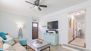 A living room with a sofa, coffee table, and a television on a cabinet.