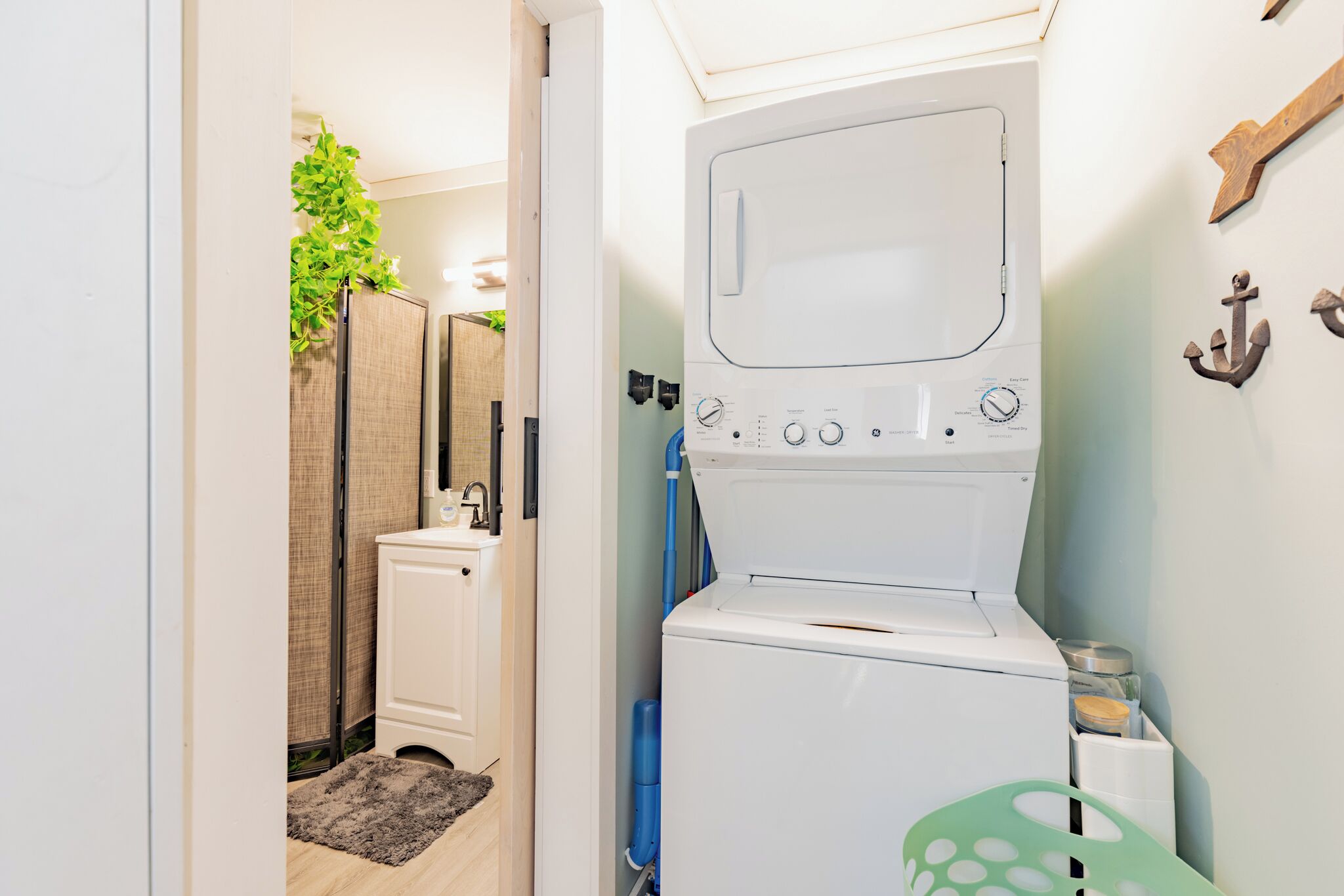 A compact laundry room with a front-loading washing machine, a small sink, and a towel rack.