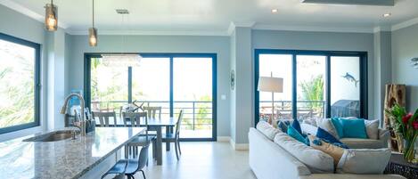 A modern kitchen with a large island, bar stools, and a dining area with a table and chairs.