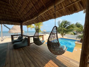 Terraza de madera con sillas colgantes y zona de piscina.