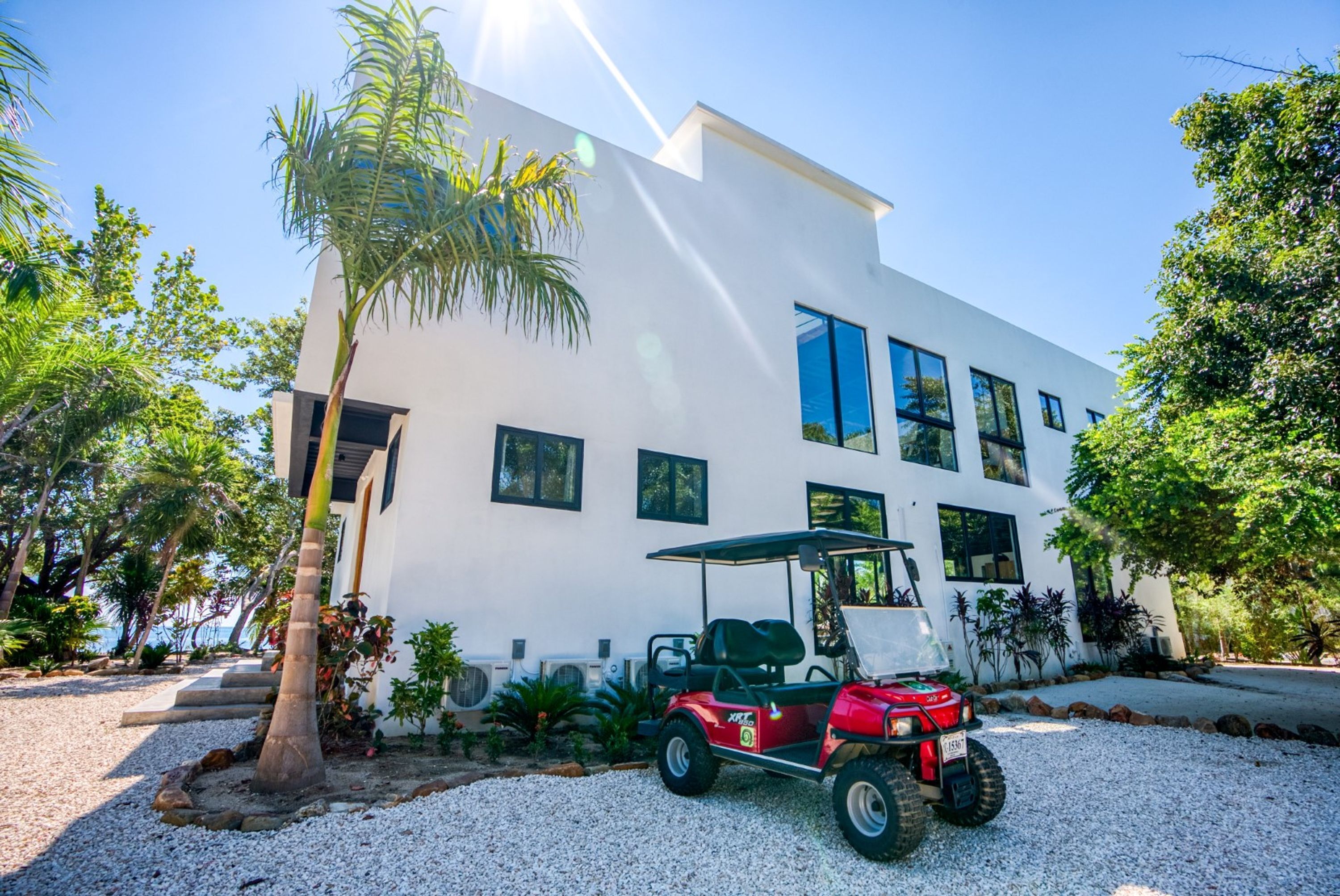 A modern white building with large windows and a red golf cart parked in front.