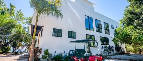 A modern white building with large windows and a red golf cart parked in front.