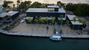 A modern coastal property with a dock, a beach area with palm trees, and a boat. - NEW Modern Ocean Front Villa on Private Island (Placencia)