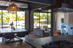Una cocina moderna con estufa a gas, ventanas amplias y una zona de comedor con mesa y sillas.