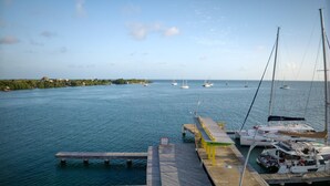 Un port de plaisance avec des bateaux amarrés, une jetée en bois et une vue sur la mer et la côte lointaine.