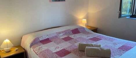 A neatly made bed with a patterned bedspread, two bedside lamps, and a framed picture on the wall.