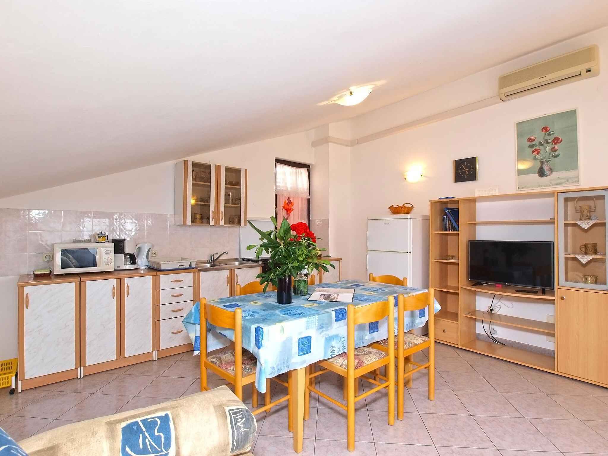 A compact kitchen with a dining area, featuring a microwave, stove, sink, and a small refrigerator.