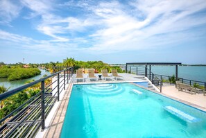A swimming pool with a view of the sea and greenery. - Oceanfront Sunset Gecko Condo - Second Floor 2B (Placencia)
