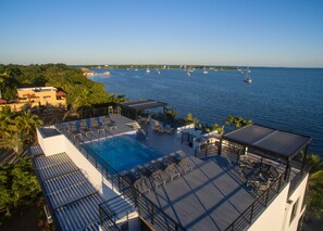 A rooftop pool with lounge chairs and a view of the sea with boats. - Oceanfront Sunset Gecko Condo - Second Floor 2B (Placencia)