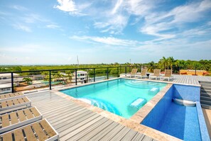 A rooftop pool with lounge chairs and a view of the surrounding landscape. - Oceanfront Sunset Gecko Condo - Second Floor 2B (Placencia)
