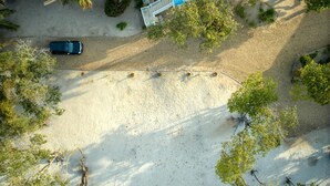 An aerial view of a parking area with a car, surrounded by trees and a building with a blue roof.