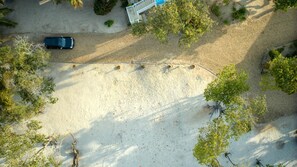 An aerial view of a parking area with a car, surrounded by trees and a building with a blue roof.