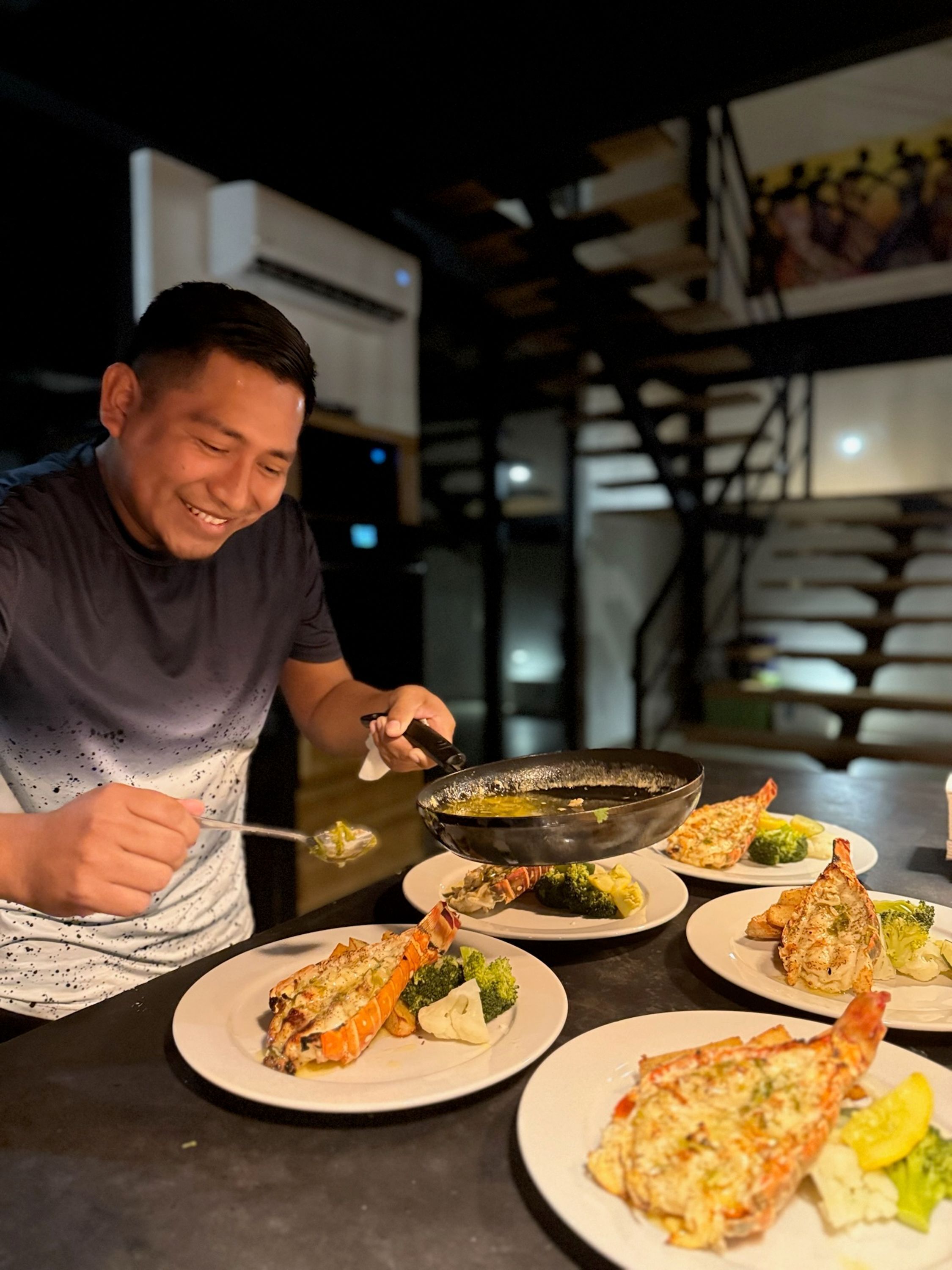 Une personne servant des plats, dont du homard, à une table.